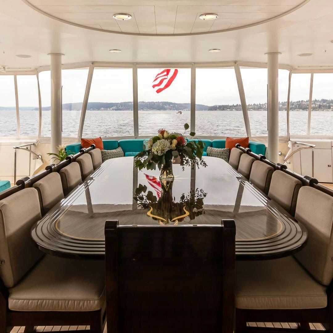 a table with chairs and a vase with flowers on it aboard SERENGETI Yacht for Sale