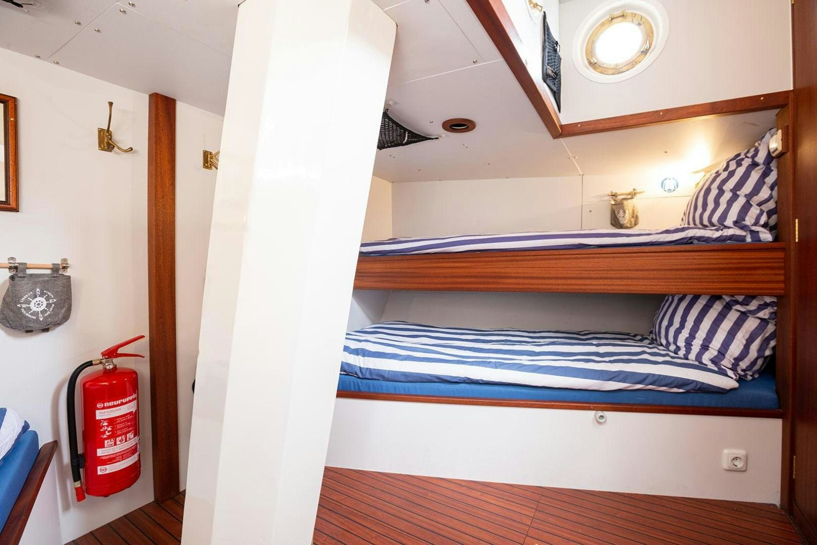 a bunk bed with a red can on the side aboard SKYTHIA Yacht for Sale