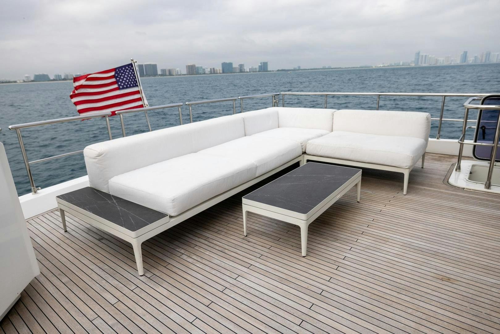 a white couch and a flag on a deck overlooking a body of water aboard HAPPY HOURS Yacht for Sale