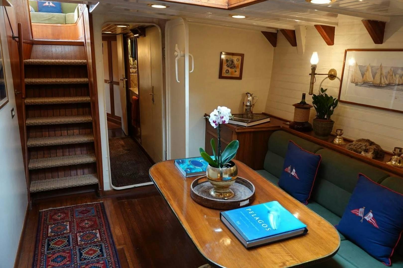 a living room with a wood table and a book on a rug aboard TAMORY Yacht for Sale