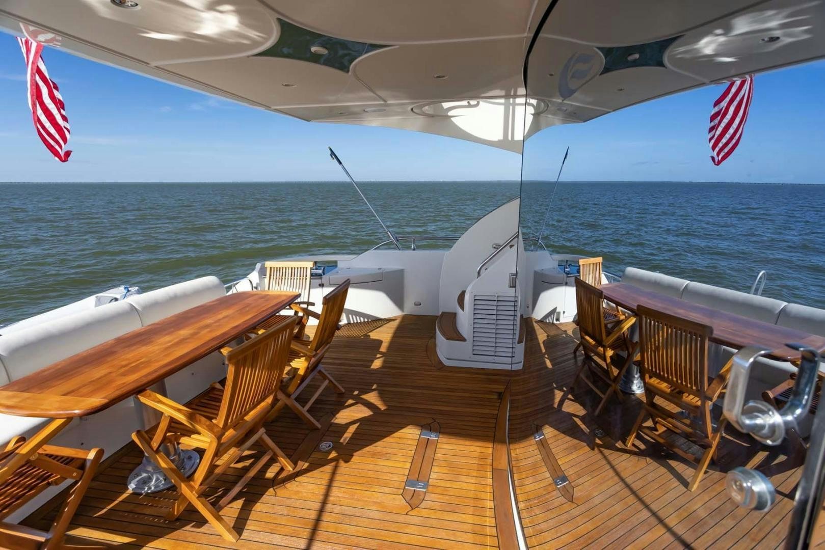 a deck of a boat with chairs and a flag on the deck aboard DECKED OUT Yacht for Sale