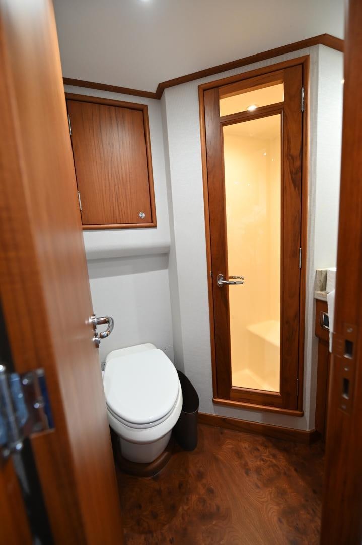 a bathroom with a toilet and wooden cabinets aboard TANGAROA Yacht for Sale