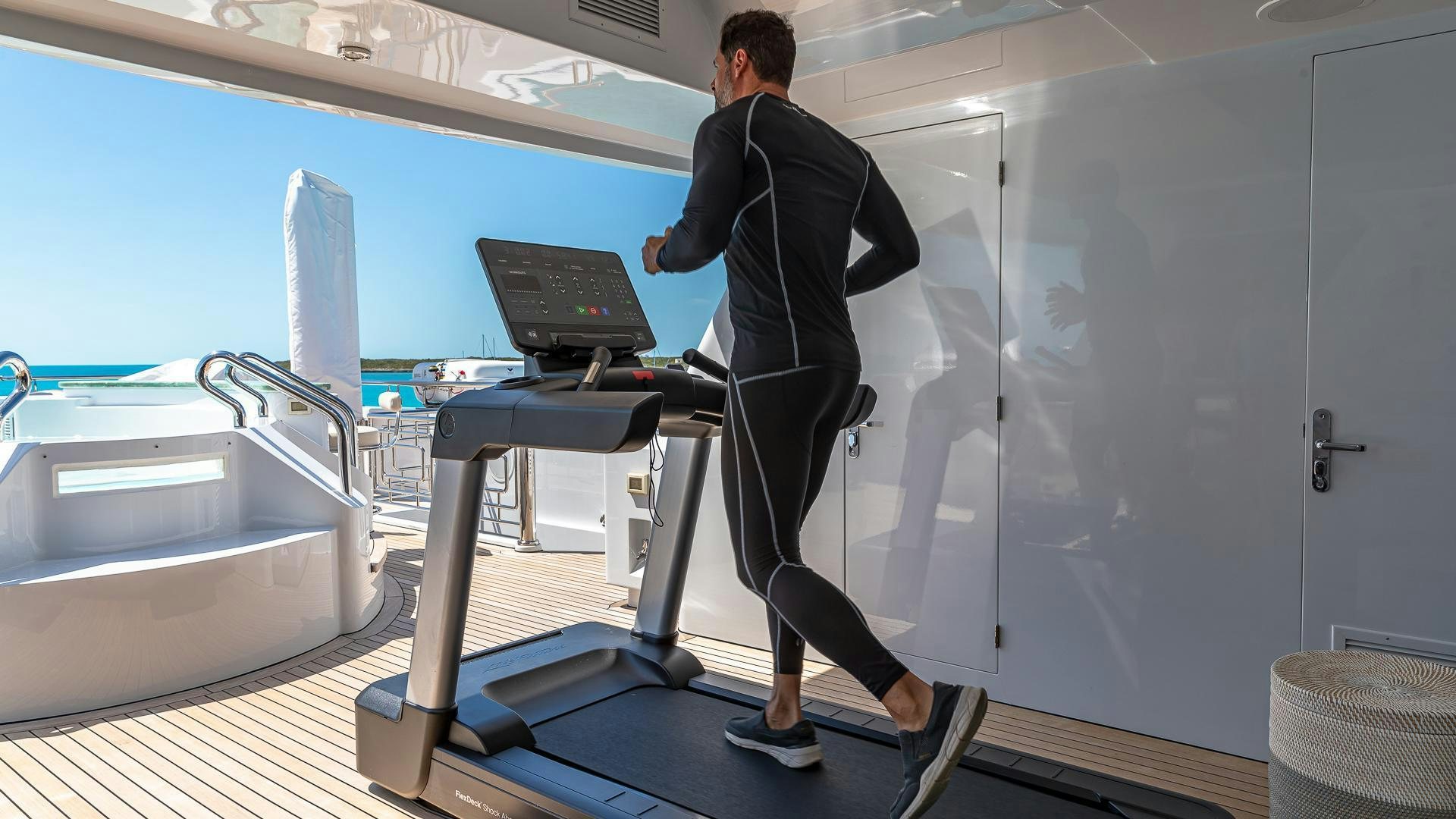 a man in a suit walking on a treadmill aboard STARSHIP Yacht for Sale