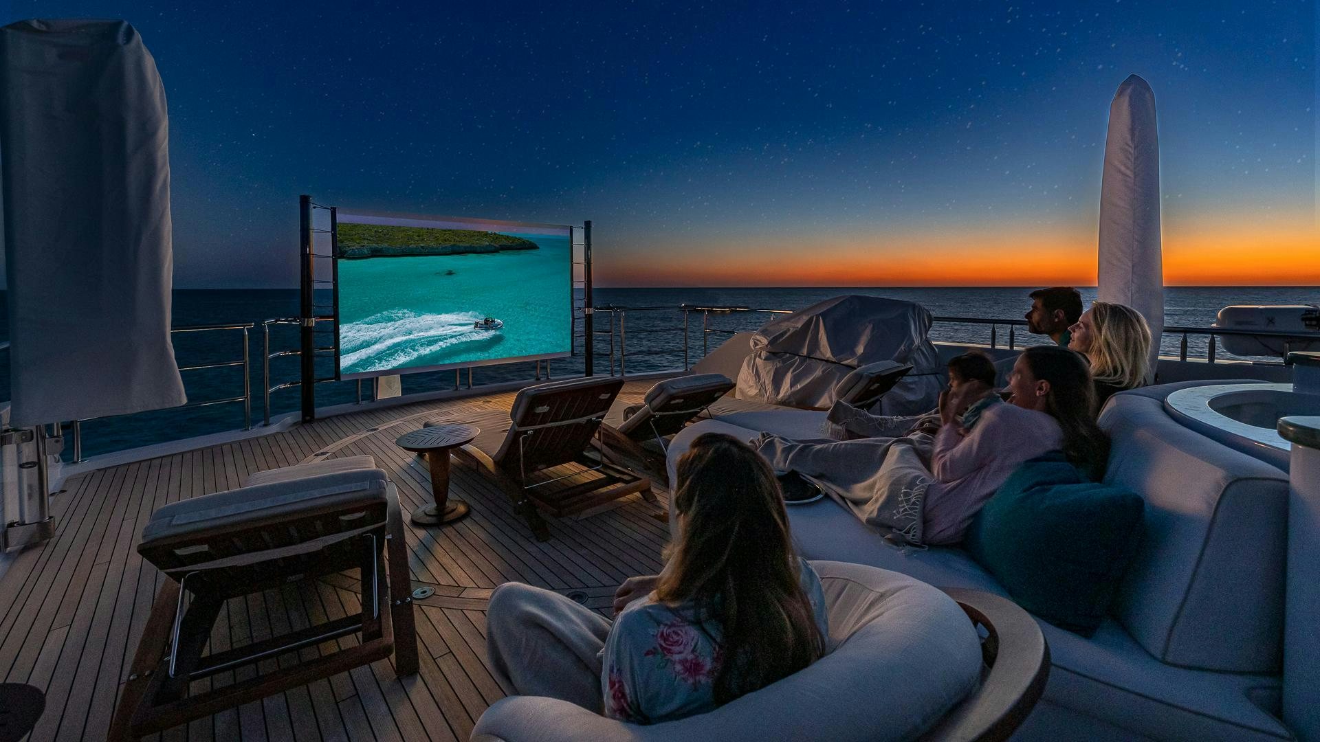 people sitting on a couch watching a television aboard STARSHIP Yacht for Sale