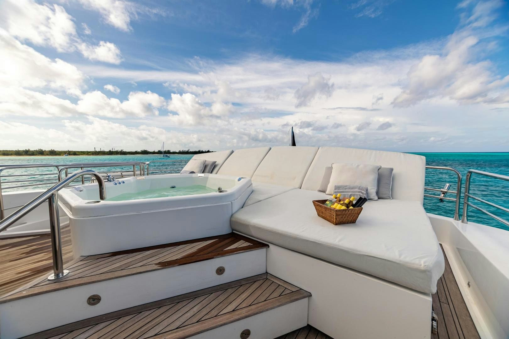 a white bathtub with a basket on it and a blue sky and clouds above aboard CORAZON Yacht for Sale