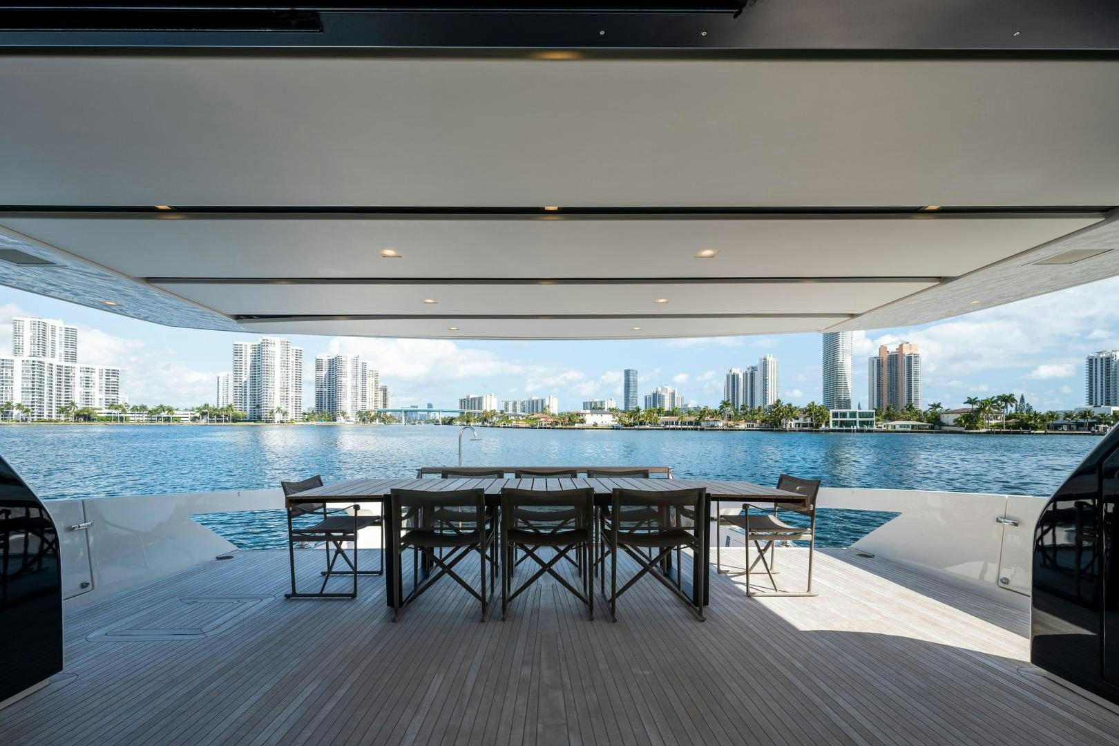 a group of tables and chairs on a deck by a body of water aboard ABOUT TIME Yacht for Sale