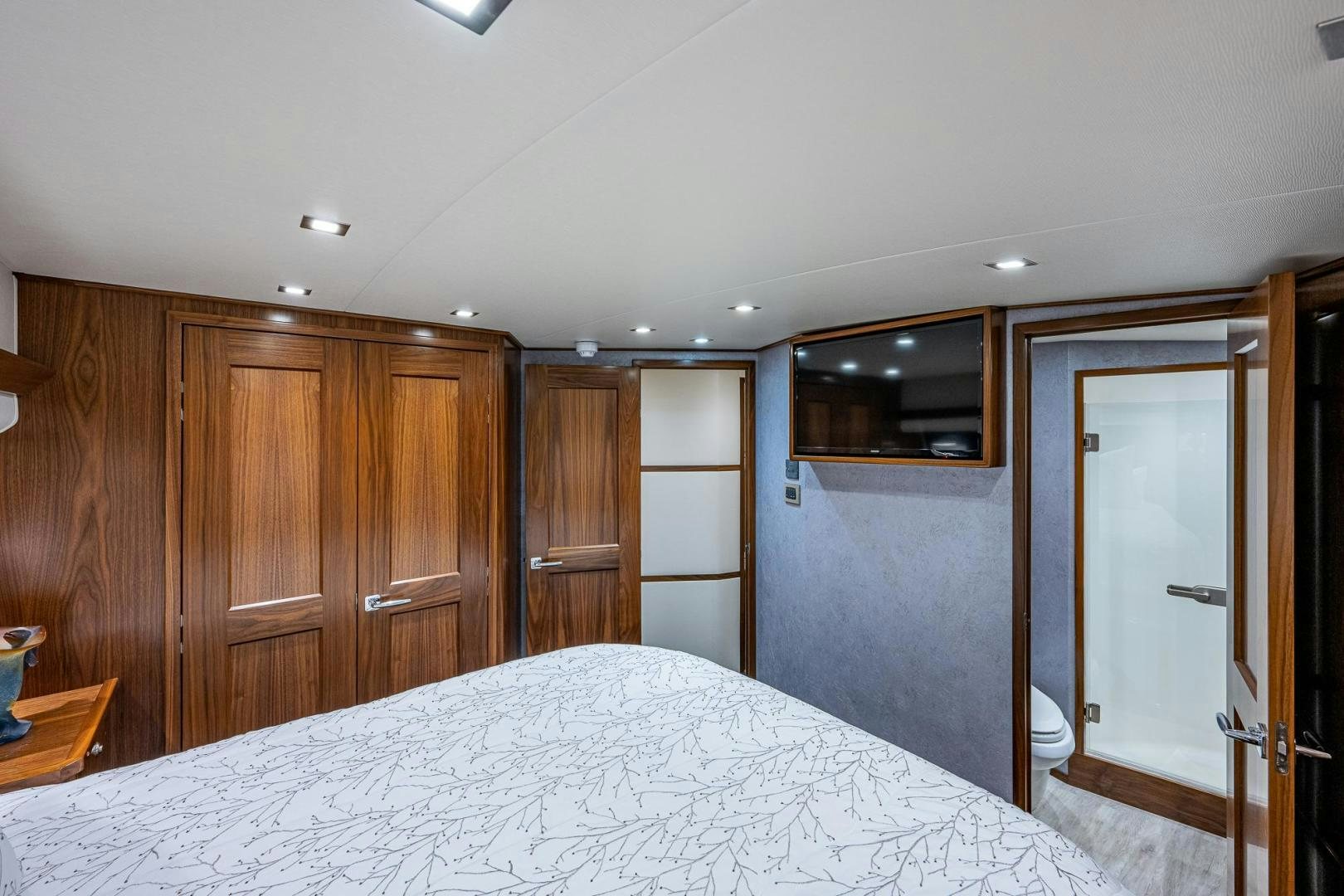 a large bedroom with a large white bed and wooden cabinets aboard KEMOSABE Yacht for Sale