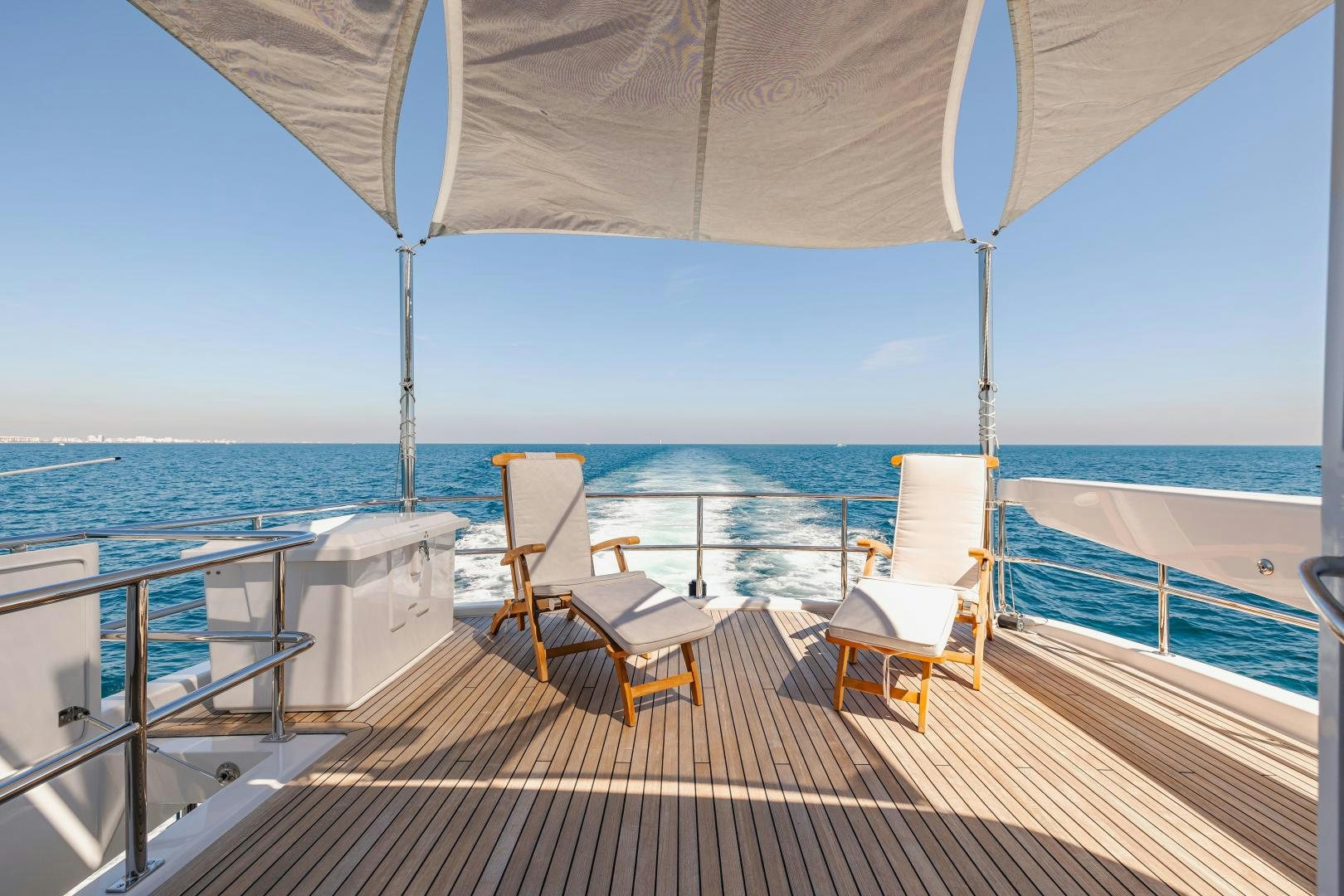 a deck with chairs and an umbrella aboard BELLA SKY Yacht for Sale