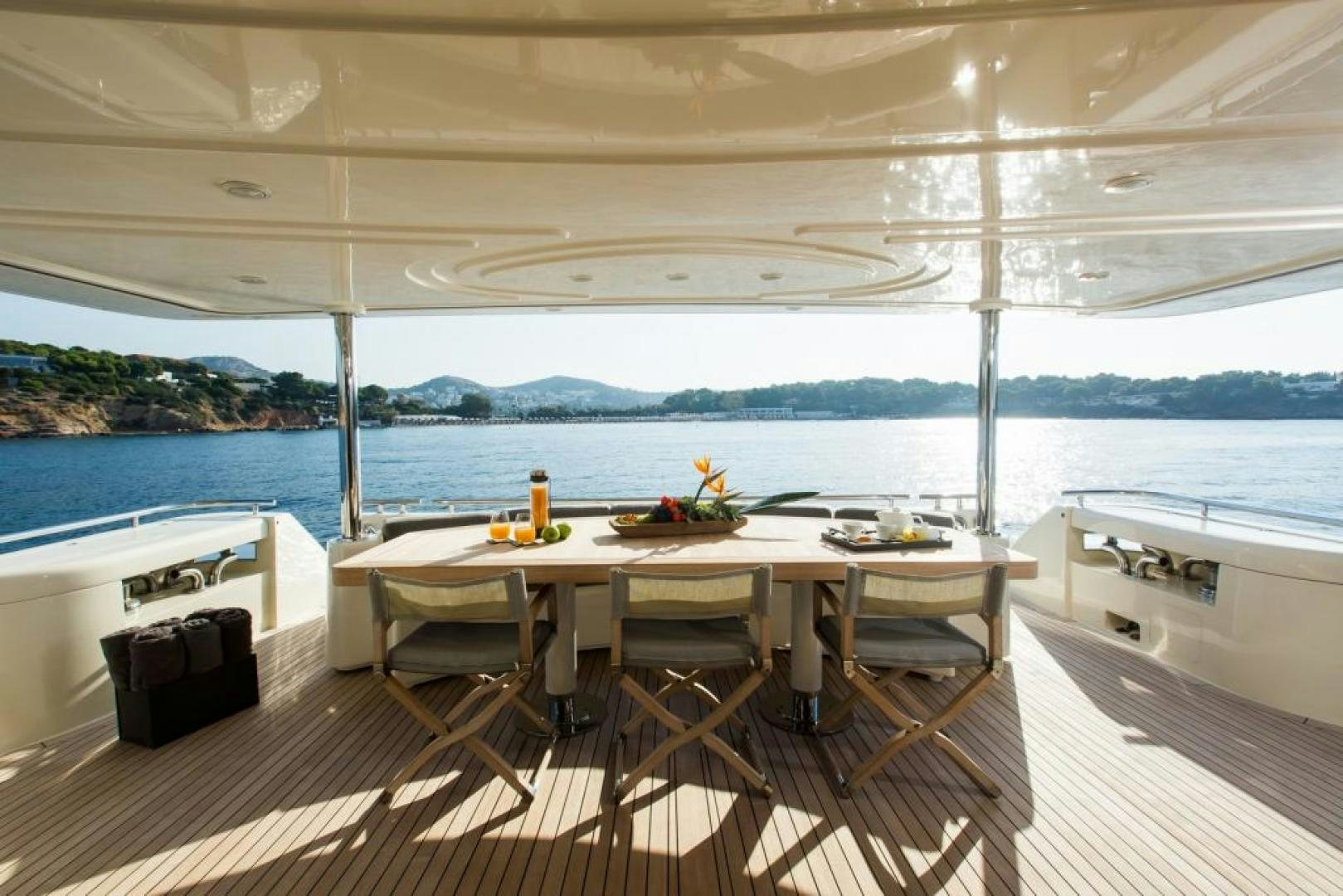 a table with chairs on a deck overlooking a body of water aboard CHAMPAGNE & CAVIAR Yacht for Sale