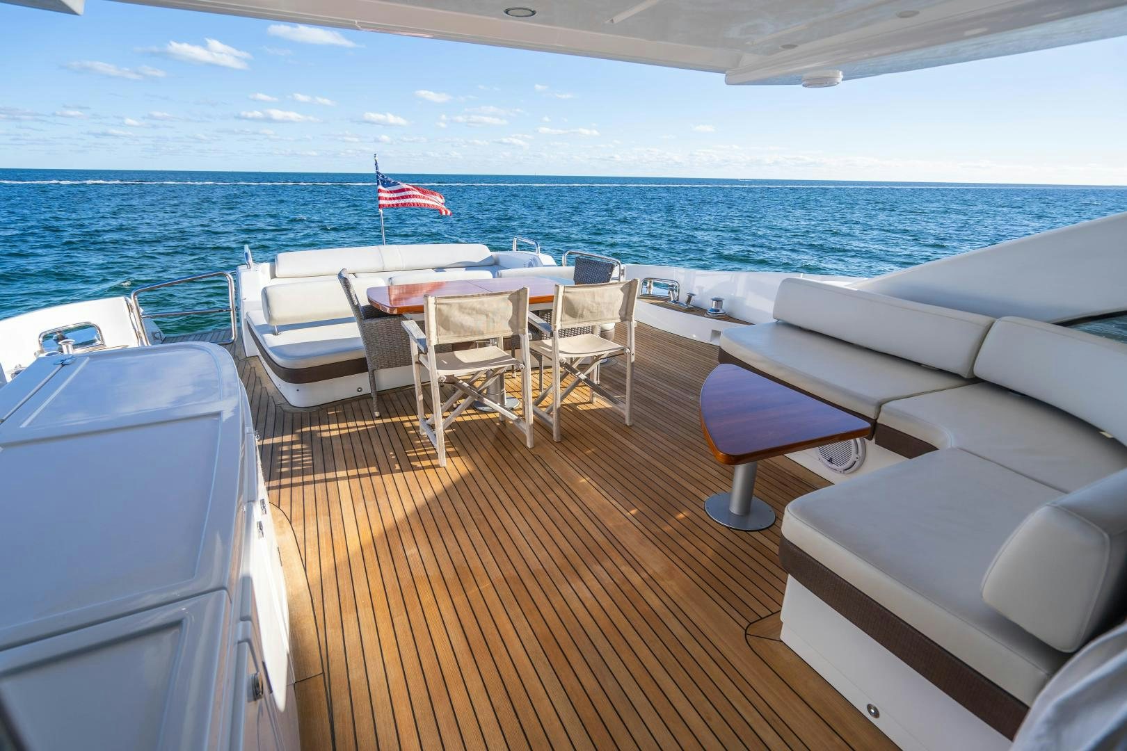 a deck with chairs and tables on it by the ocean aboard PLANE II SEA Yacht for Sale