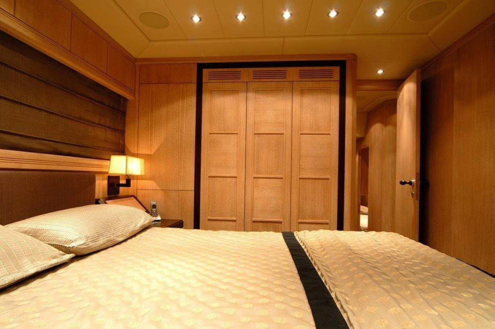 a bed with a white sheet and a wooden door aboard ARES Yacht for Sale