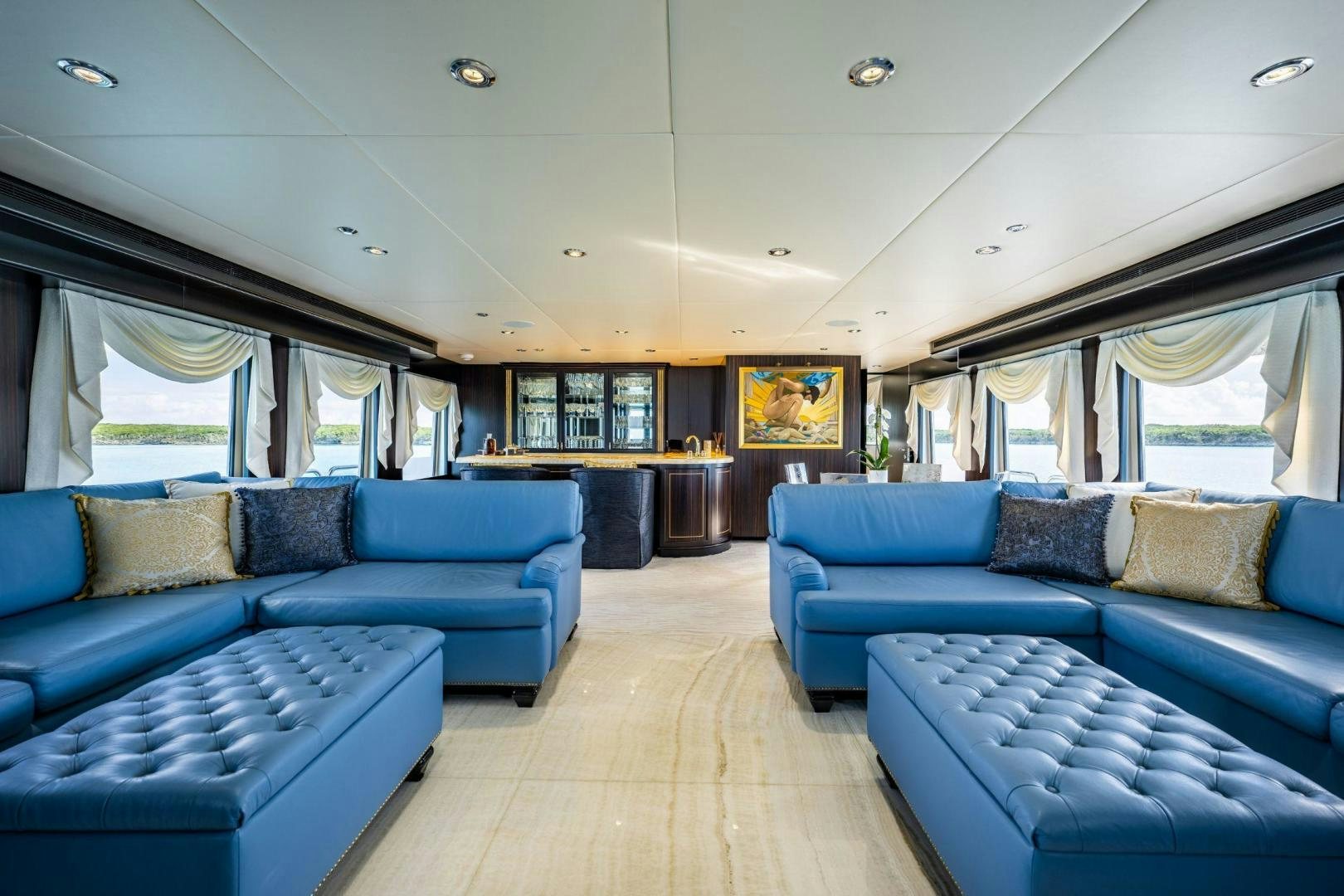 a large living room with blue couches aboard GRADE I Yacht for Sale