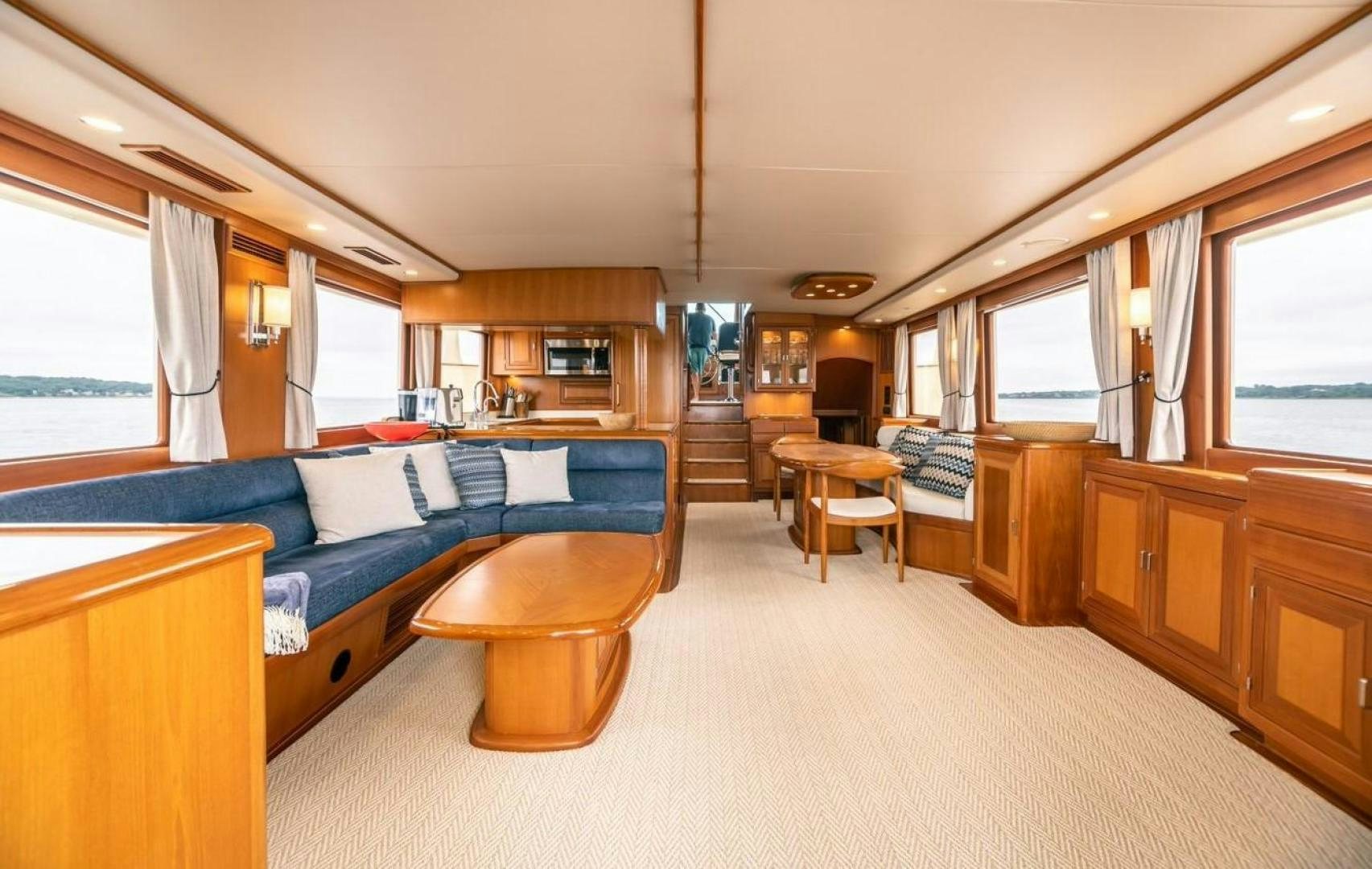 a large living room with a blue couch and wood cabinets aboard PRETTY LADY Yacht for Sale