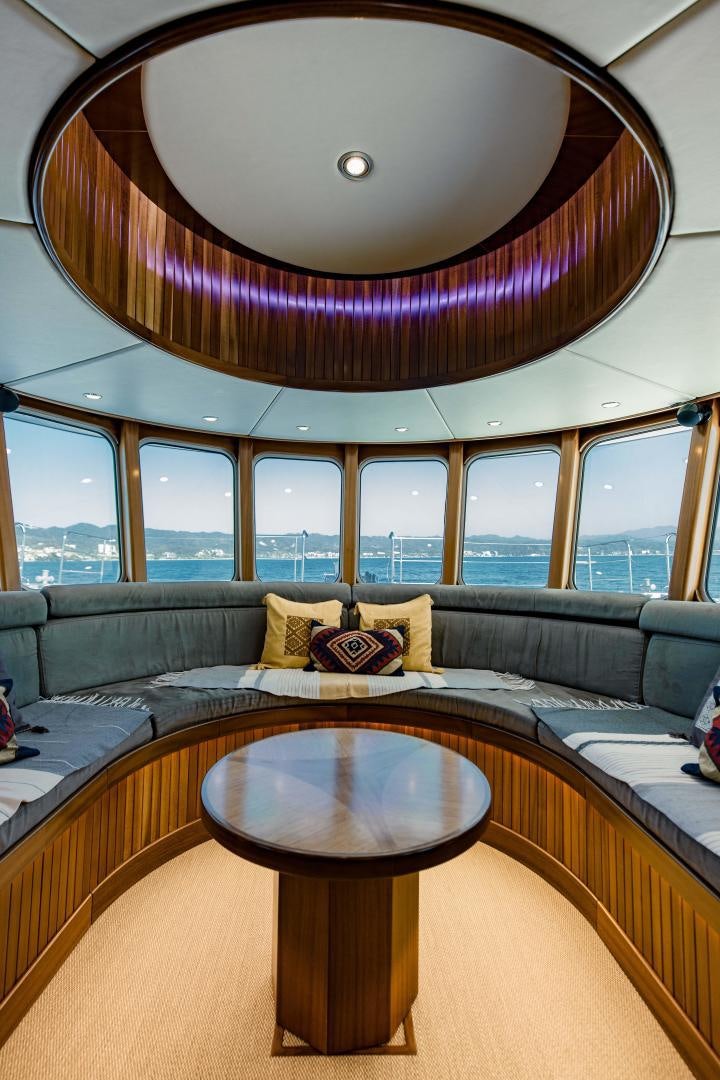 a room with a couch and a table with a view of a city aboard IETA Yacht for Sale