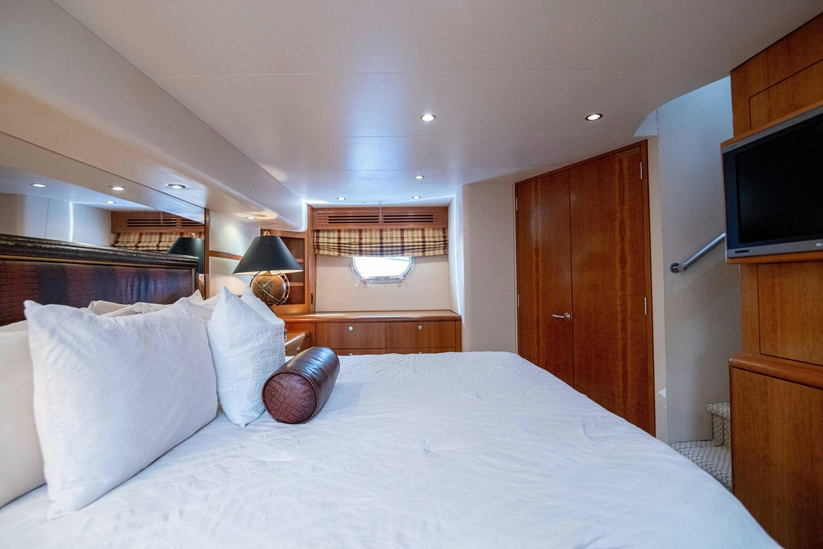 a bed with a white sheet and pillows in a room with wood cabinets aboard IONA LOUISE Yacht for Sale