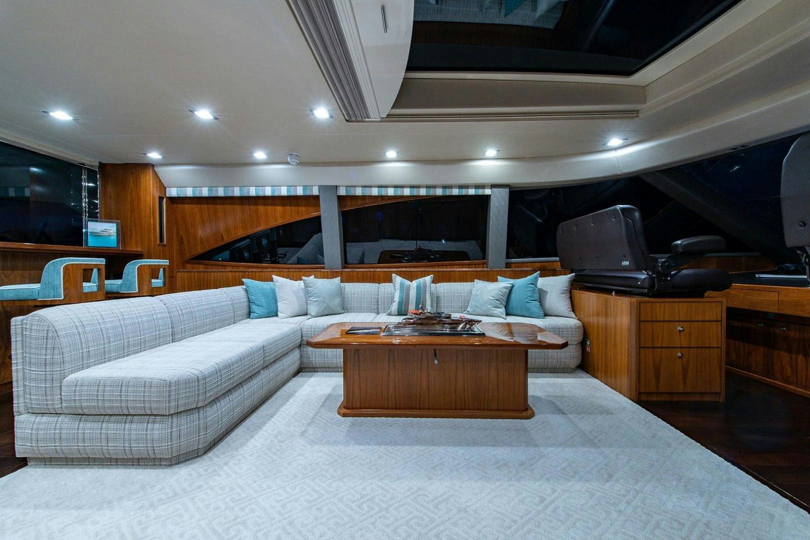 a large living room with a large white couch and a wood coffee table aboard OBSESSION Yacht for Sale
