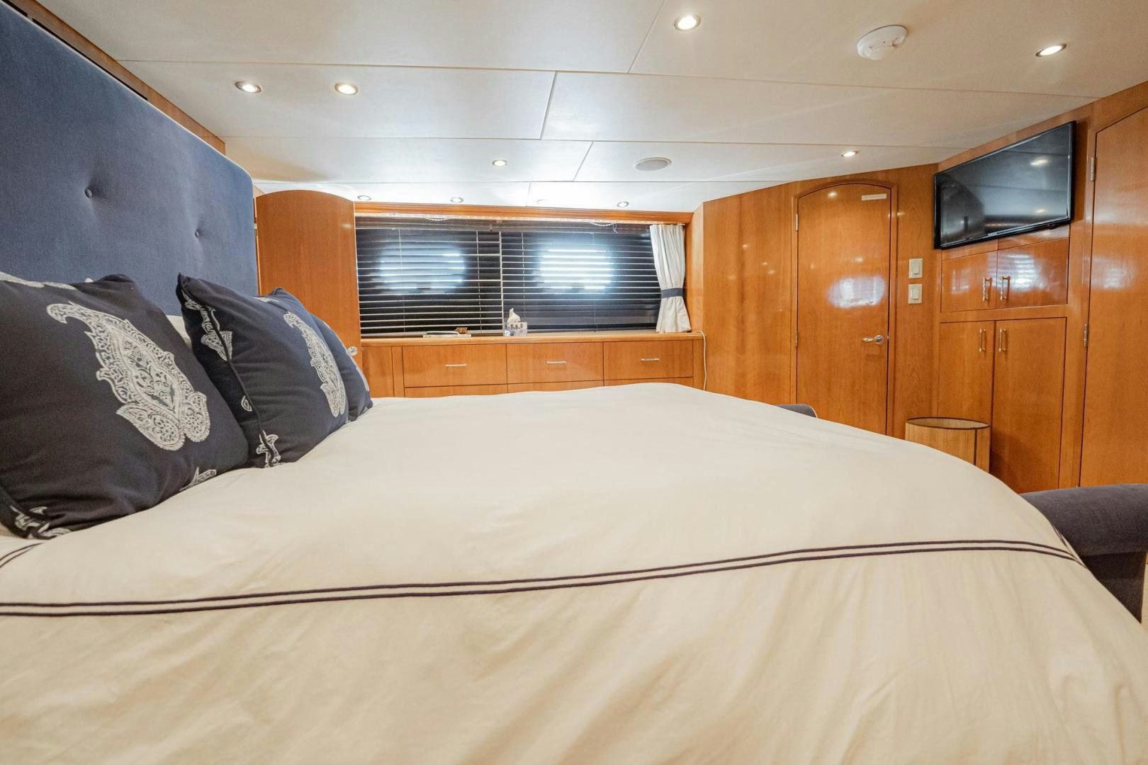 a bed with a white sheet and pillows in a room with wood cabinets aboard CRISTINA Yacht for Sale
