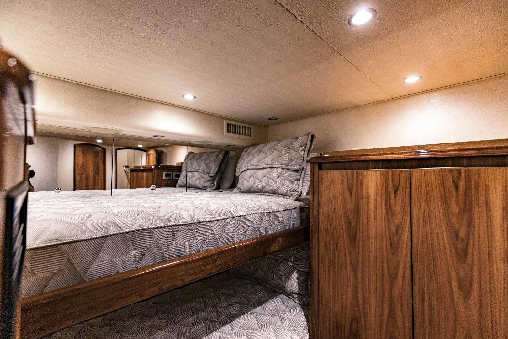 a bedroom with a bed and a wood cabinet aboard SHOE Yacht for Sale