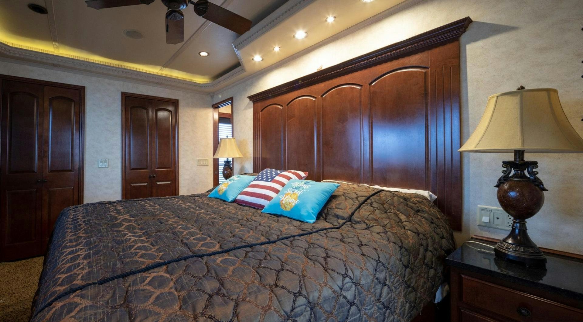 a bed with a blue and white blanket and a lamp on a table aboard KNOT TIDE DOWN Yacht for Sale