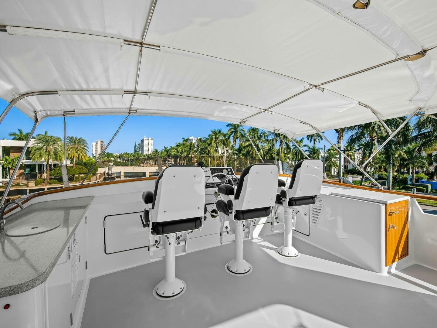 a group of white chairs on a white table in a room with trees and a blue sky aboard SIENNA Yacht for Sale