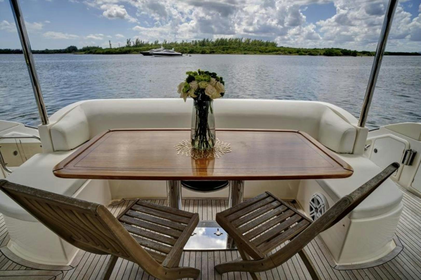 a table with chairs and flowers on it by a body of water aboard WICKED Yacht for Sale