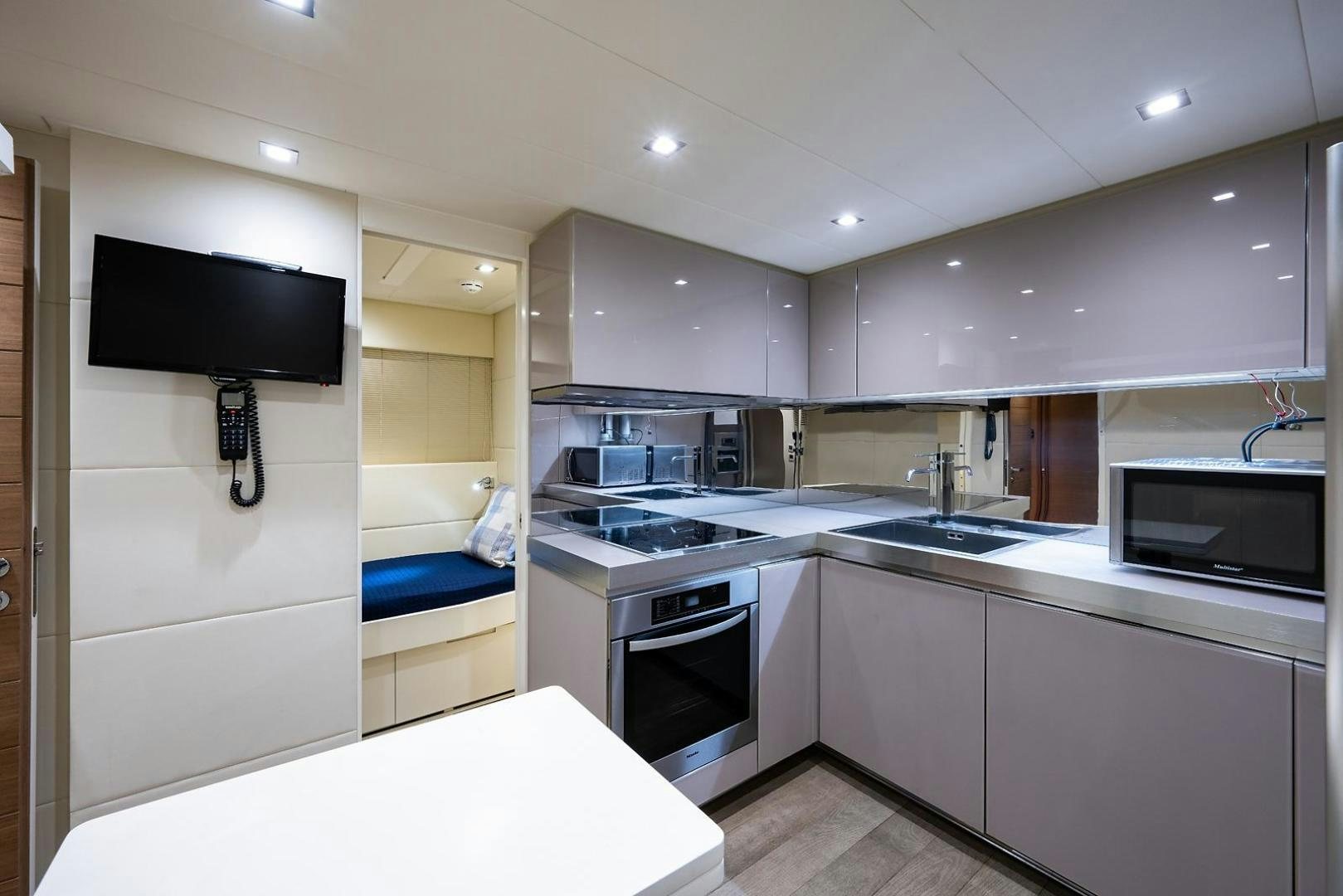 a kitchen with a tv and a bed aboard IMAGINE Yacht for Sale