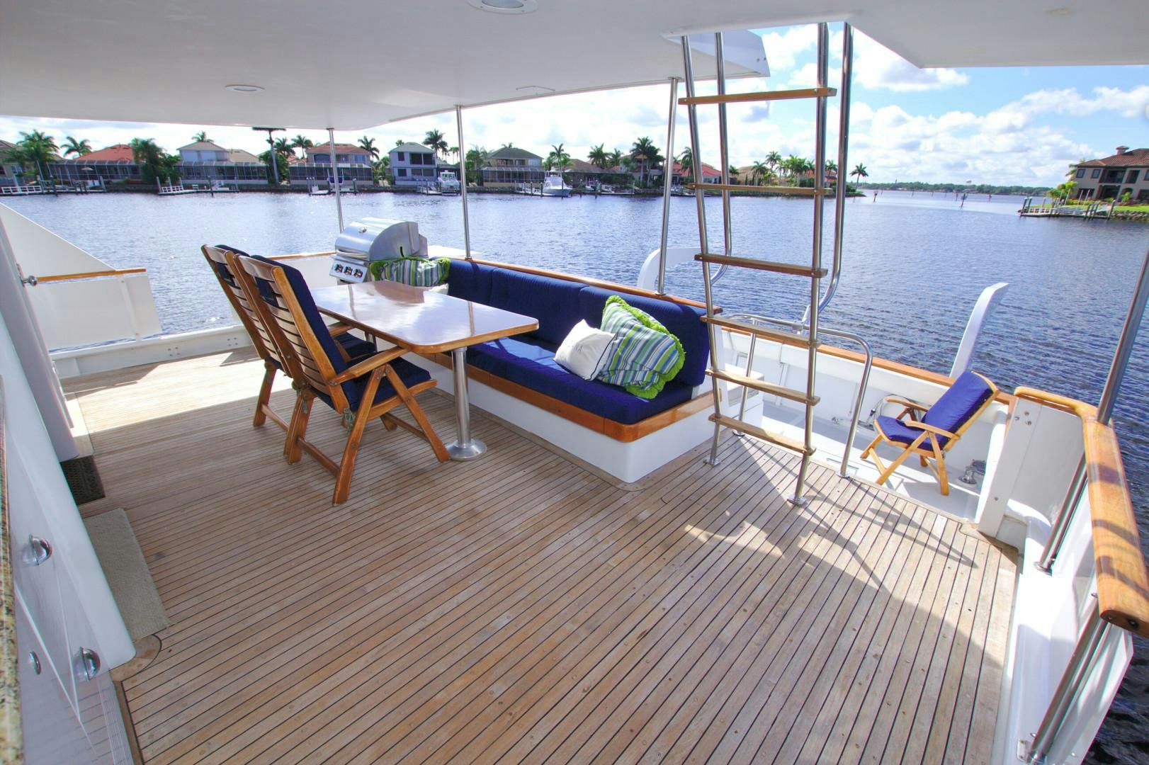 a deck with a table chairs and a boat in the water aboard PENDANA Yacht for Sale