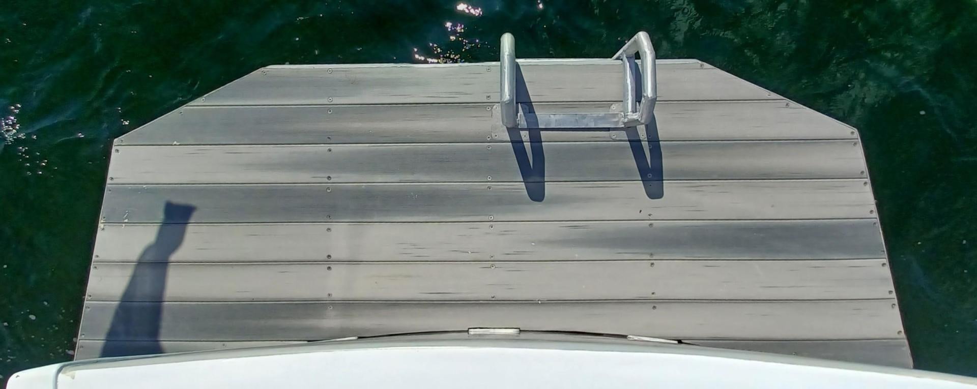 a wood deck with a blue railing aboard TARA Yacht for Sale