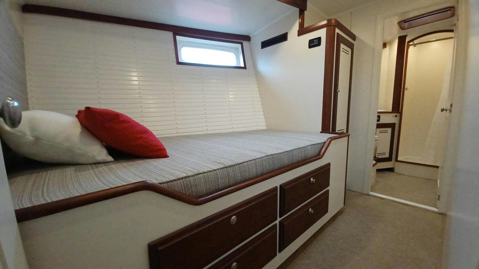 a bed with a red pillow aboard TARA Yacht for Sale