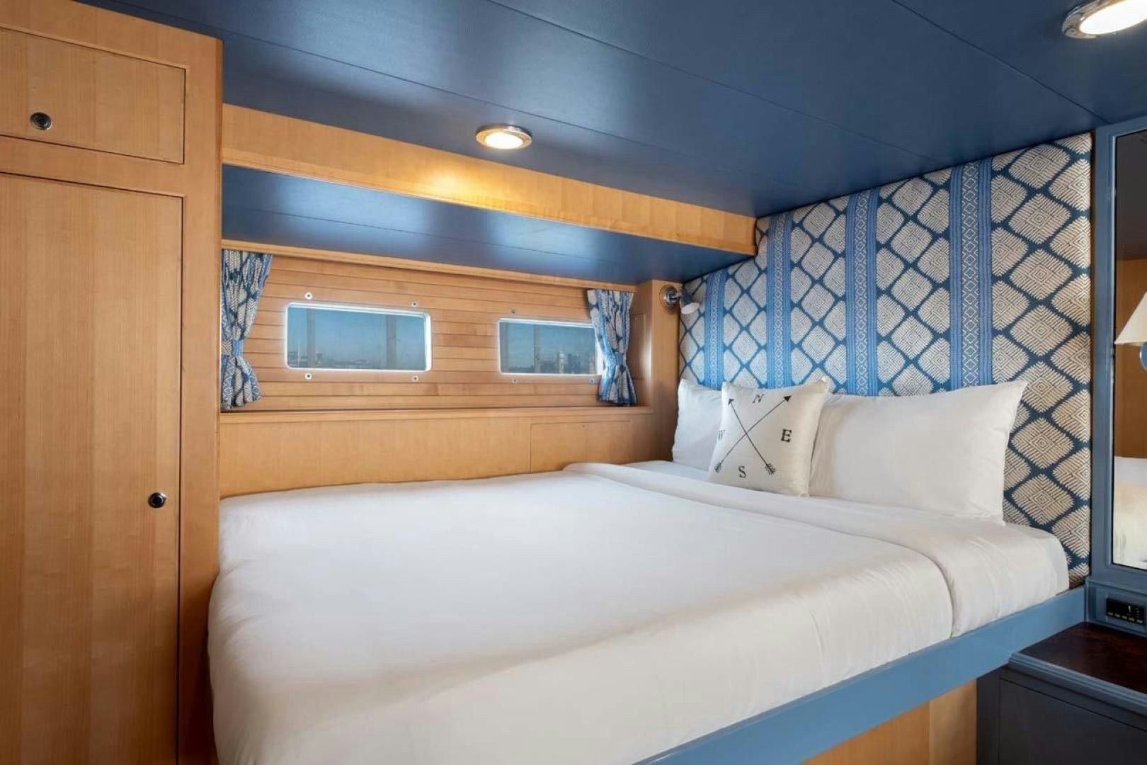 a bed with a blue wall aboard PIVOT Yacht for Sale