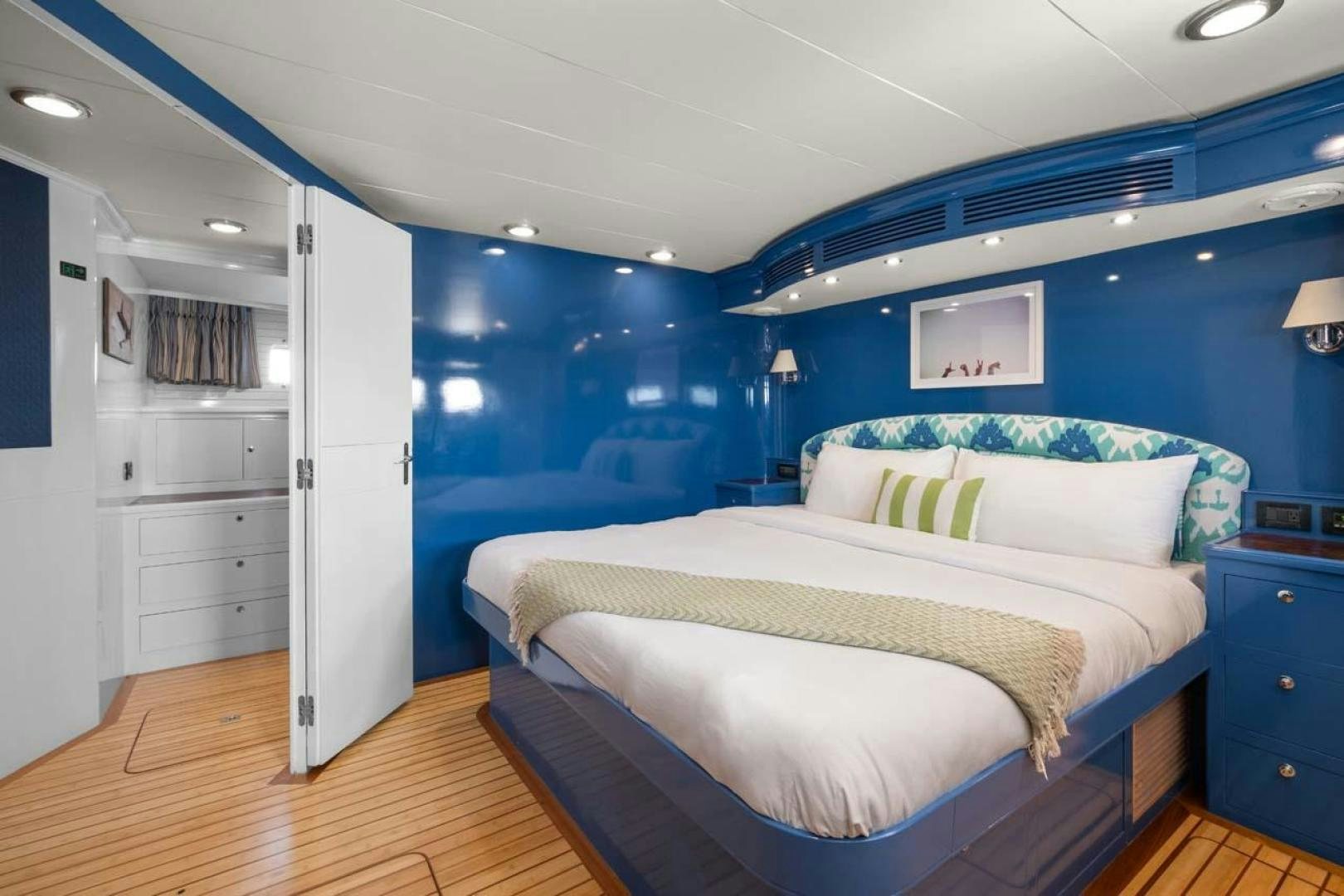 a bedroom with a blue wall aboard PIVOT Yacht for Sale