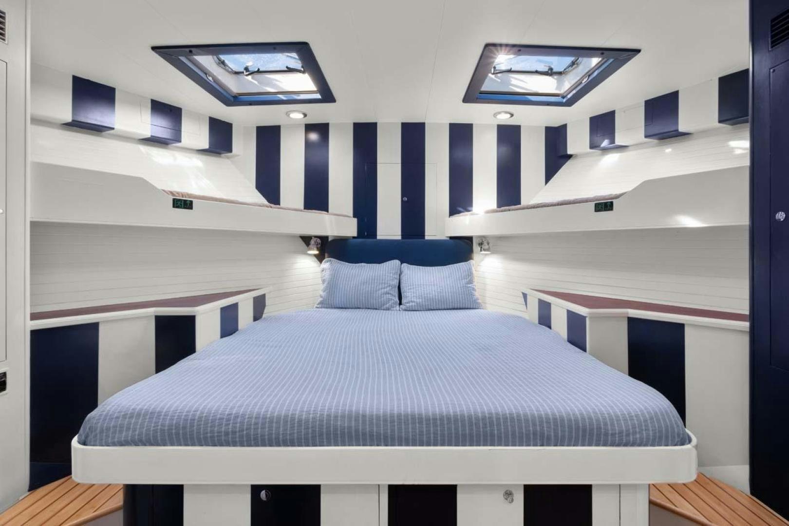 a bed with blue sheets aboard PIVOT Yacht for Sale