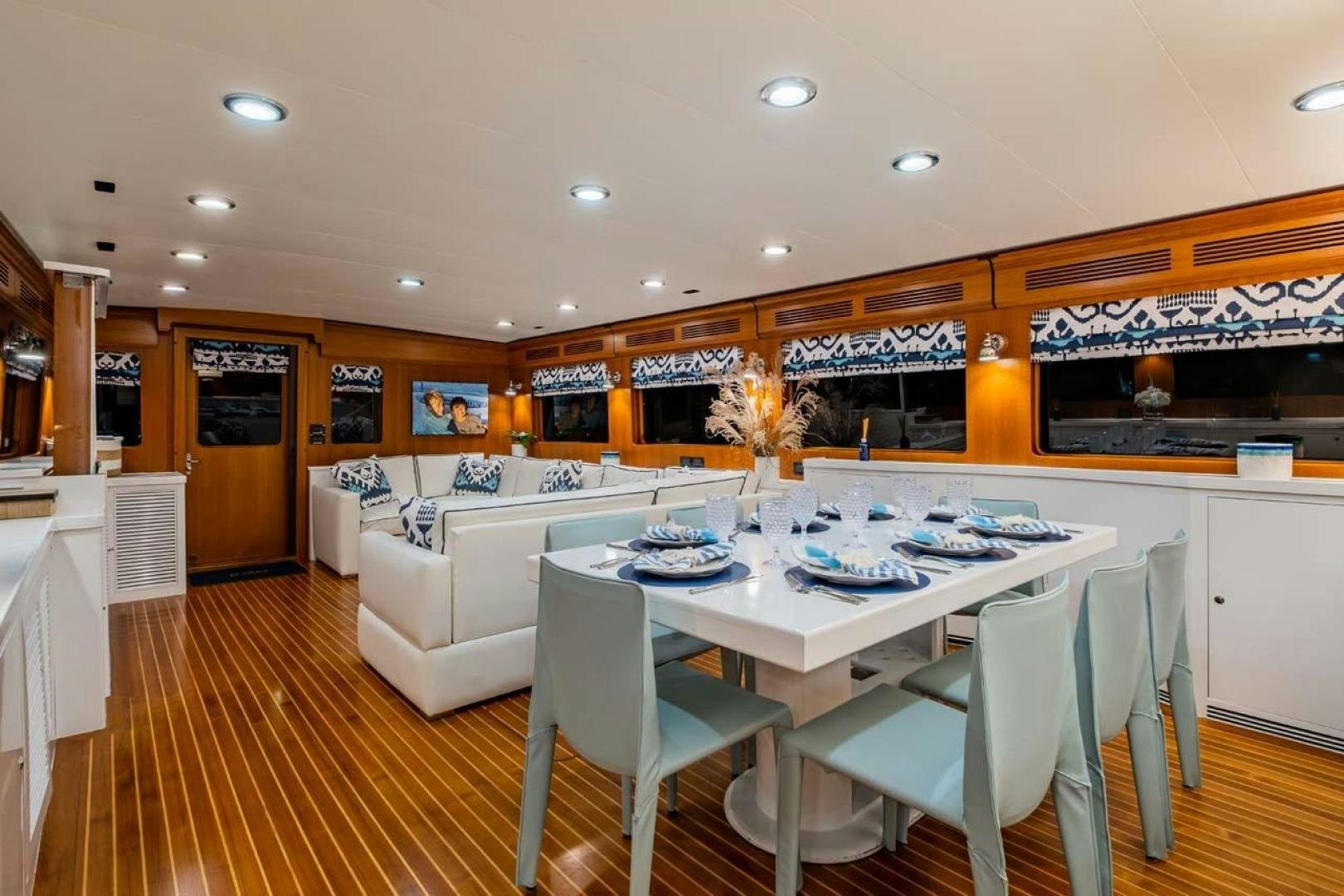 a large white dining table in a room with a large white couch and a large window aboard PIVOT Yacht for Sale