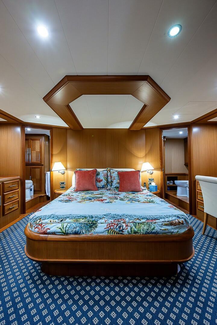 a bed with a blue and white rug and a wooden headboard aboard KNOT NANNY'S Yacht for Sale