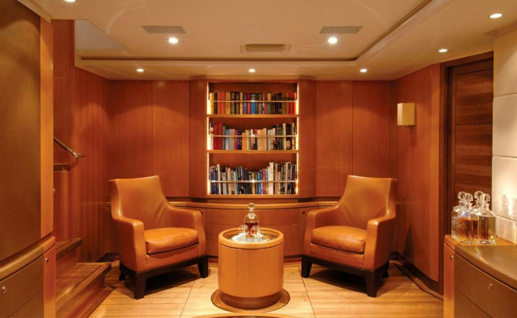 a room with a table chairs and a shelf with books aboard ARISTARCHOS Yacht for Charter