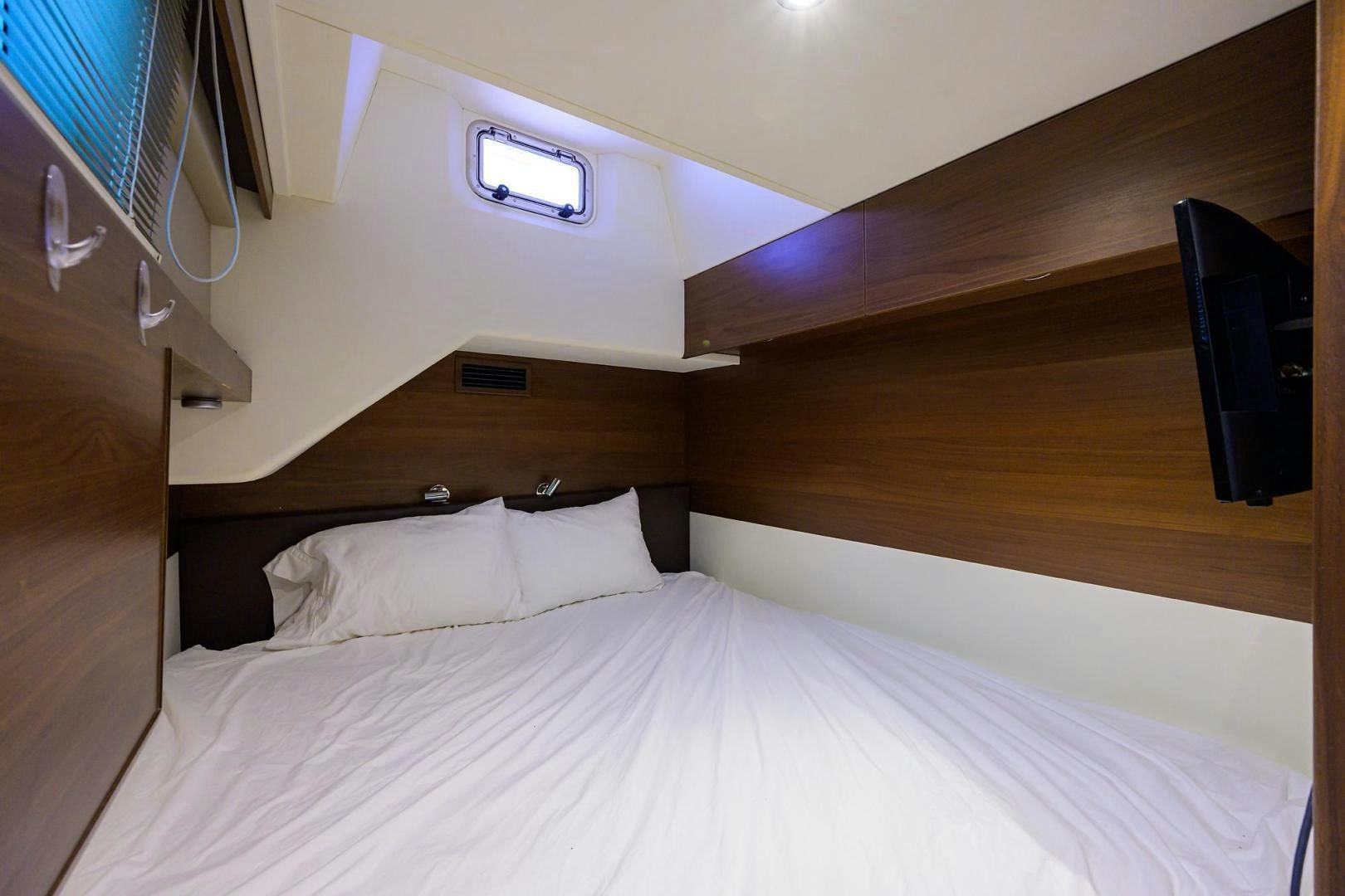 a bed with a white sheet and a wooden headboard aboard KHATCH YOU LATER Yacht for Sale