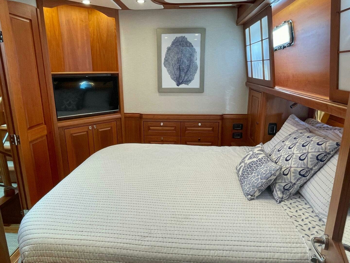a bed with a white sheet and pillows in a room with wood cabinets aboard WHIRL AWAY Yacht for Sale