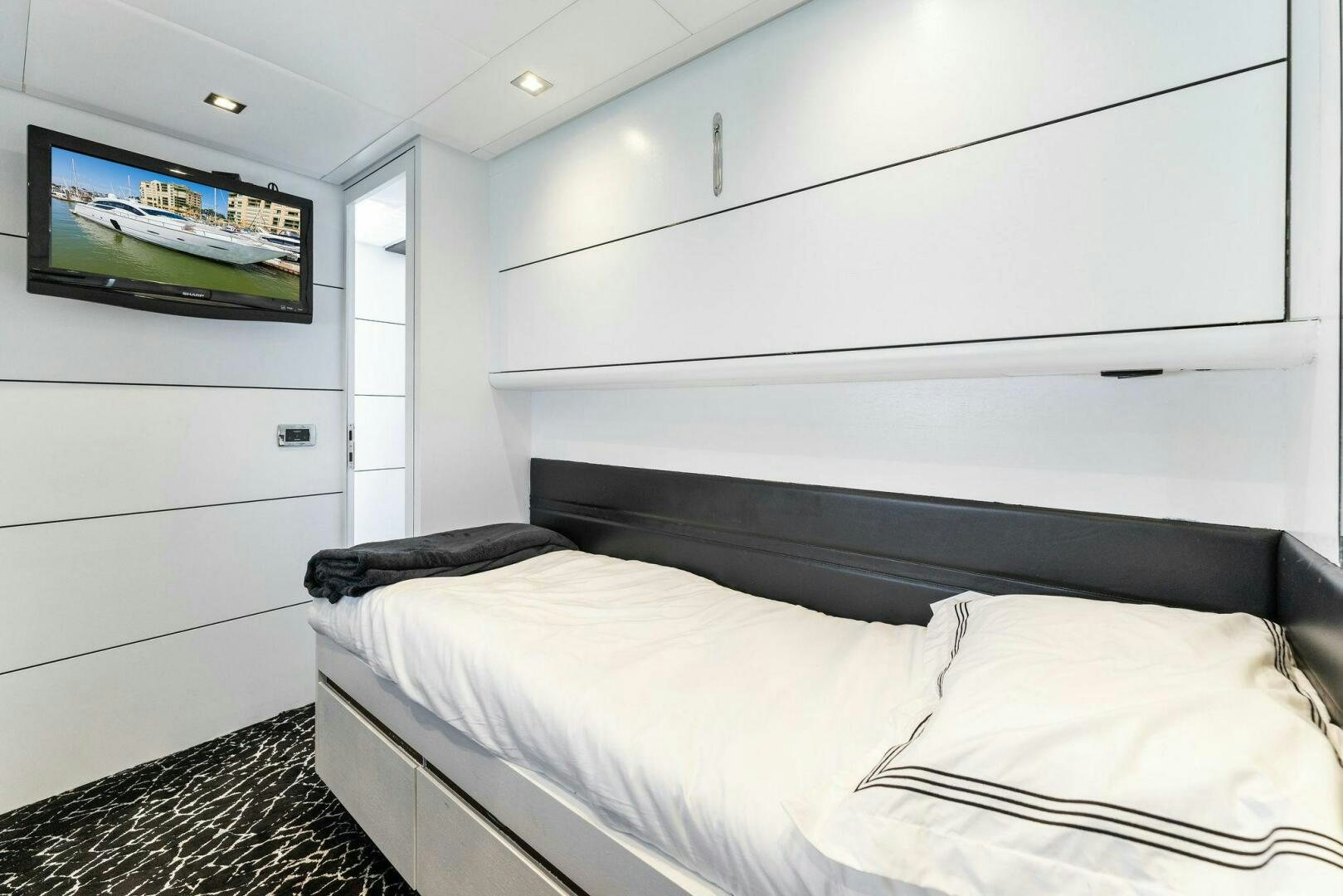 a room with a bed and a television on the wall aboard HAWK Yacht for Sale