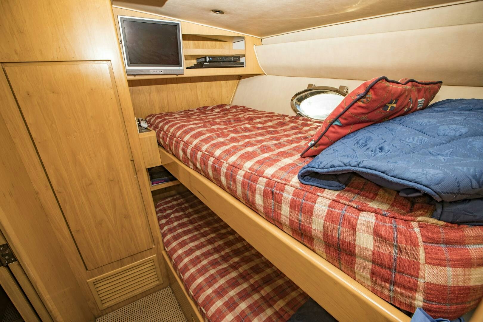 a bed with a red and blue blanket aboard GOOD KARMA Yacht for Sale