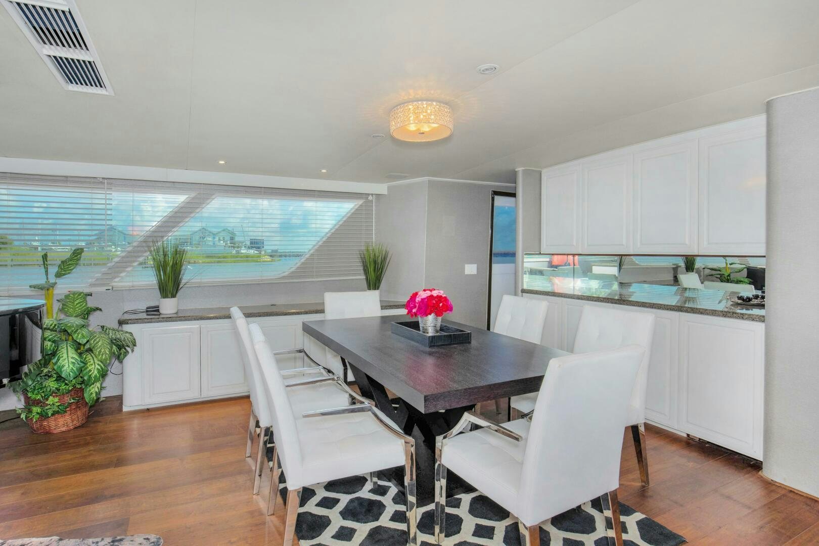 a kitchen with white chairs and a table with plants on it aboard LADY P Yacht for Sale