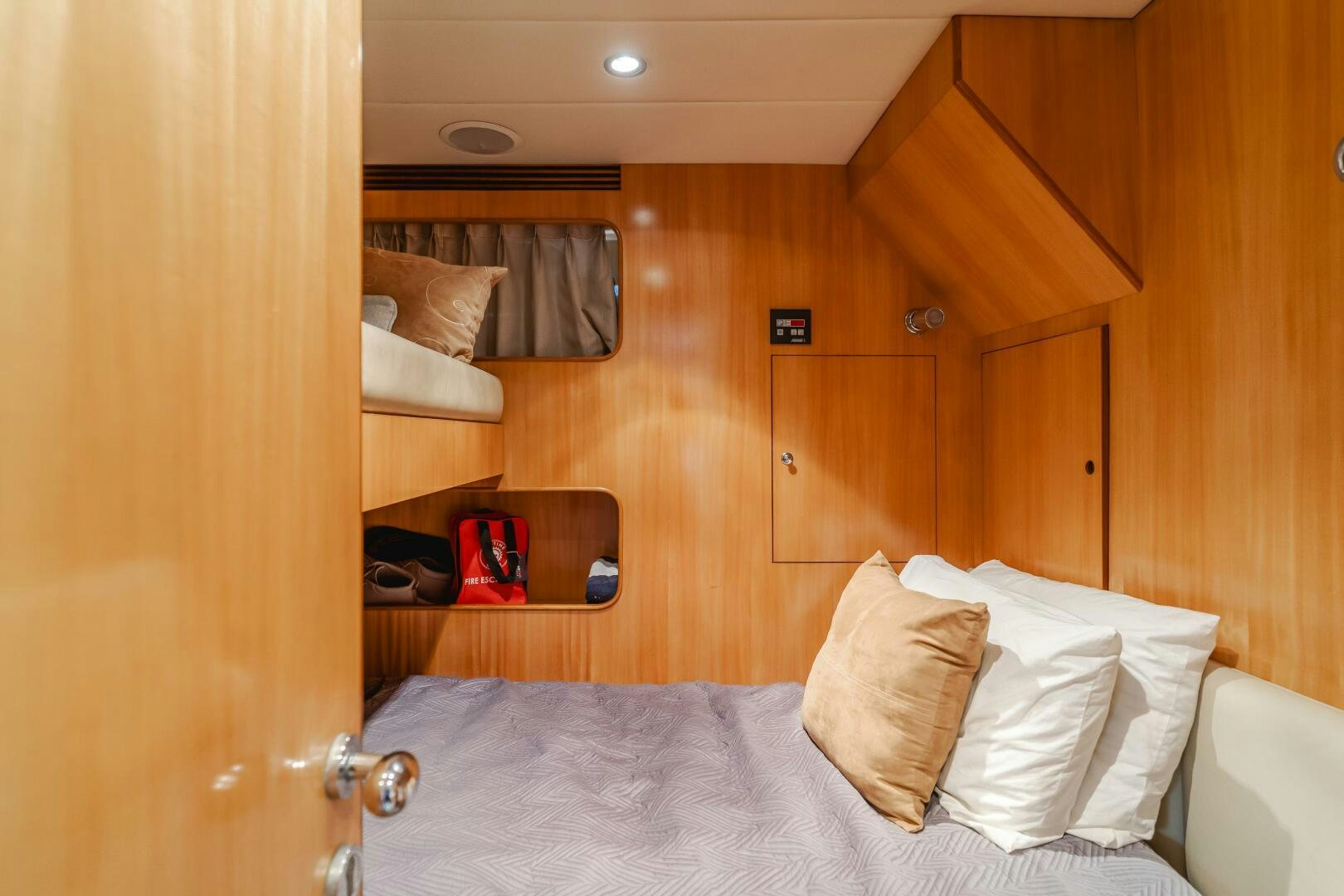 a bed with a white sheet and pillows in a room with wood cabinets aboard LADY LAURA Yacht for Sale