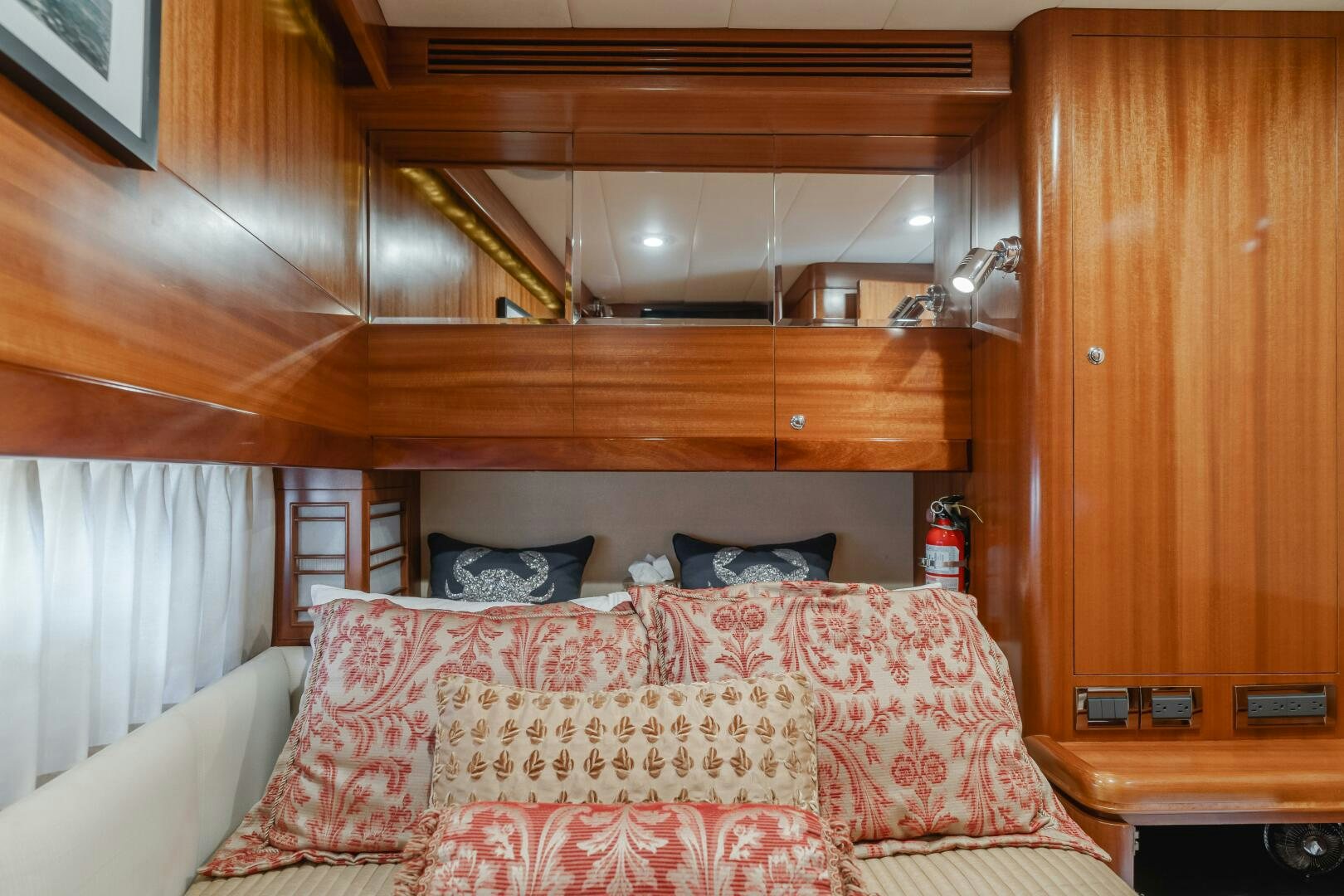 a bed with a red and white pillow and a wooden headboard aboard LADY LAURA Yacht for Sale