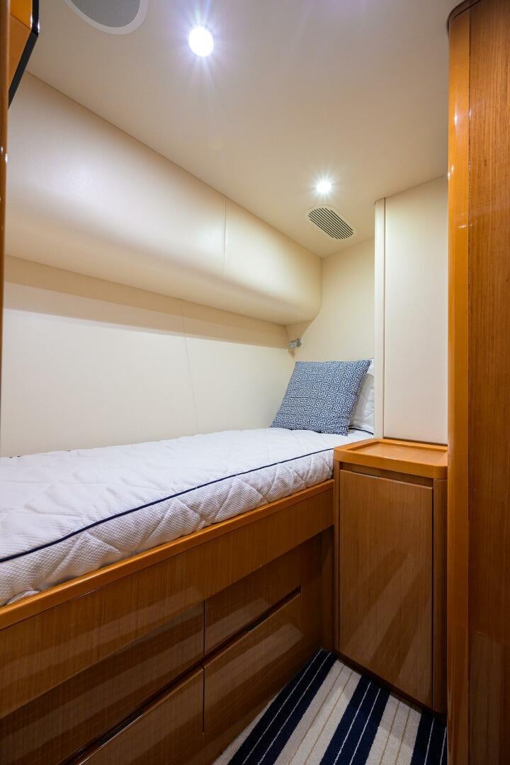 a bedroom with a bed and a blue and white striped rug aboard GOIN DEEP Yacht for Sale