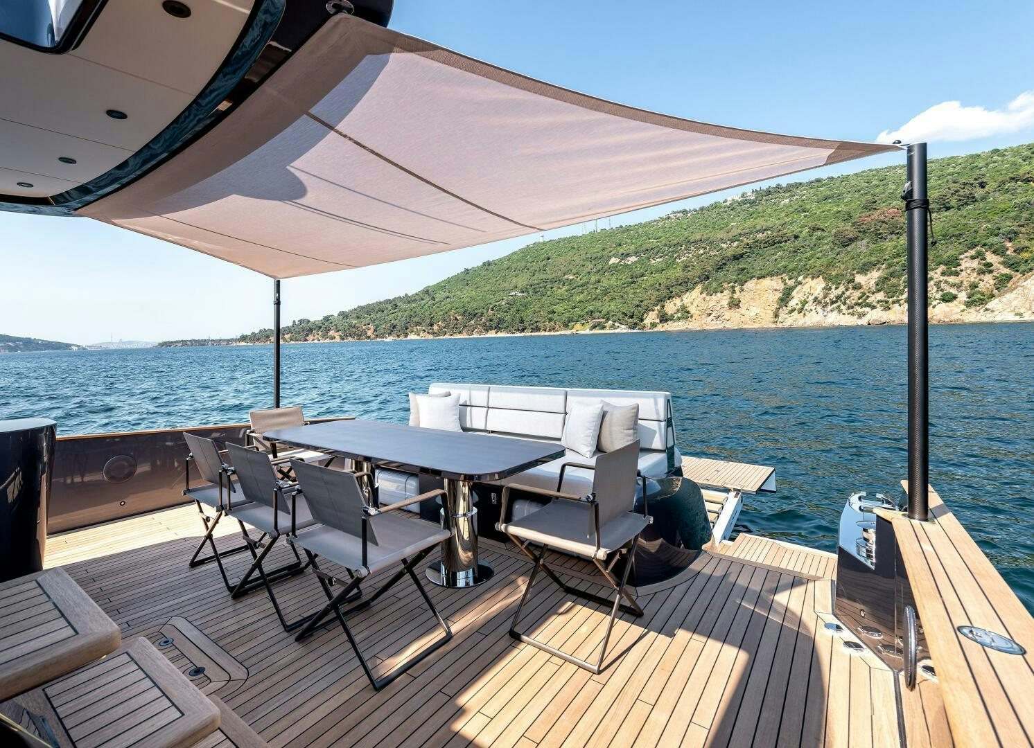 a deck with a table and chairs on it by the water aboard SUNYA Yacht for Sale