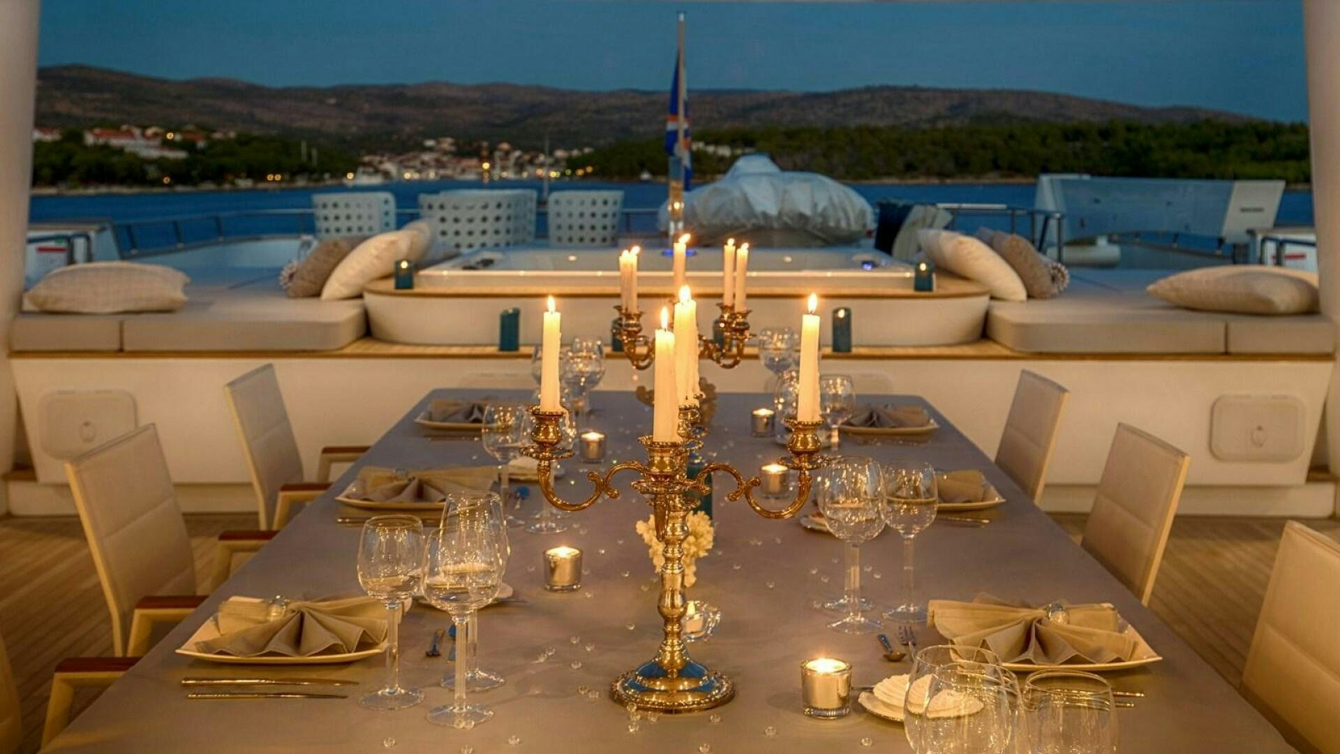 a table with candles and a large body of water in the background aboard KATINA Yacht for Sale