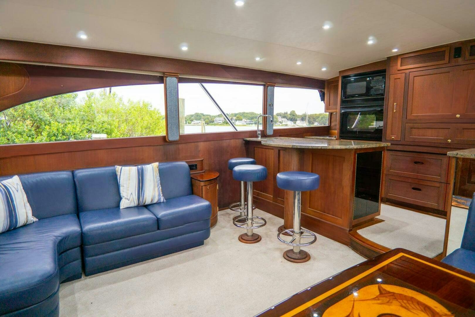 a living room with a blue couch and a wood cabinet aboard BIG BLUE Yacht for Sale