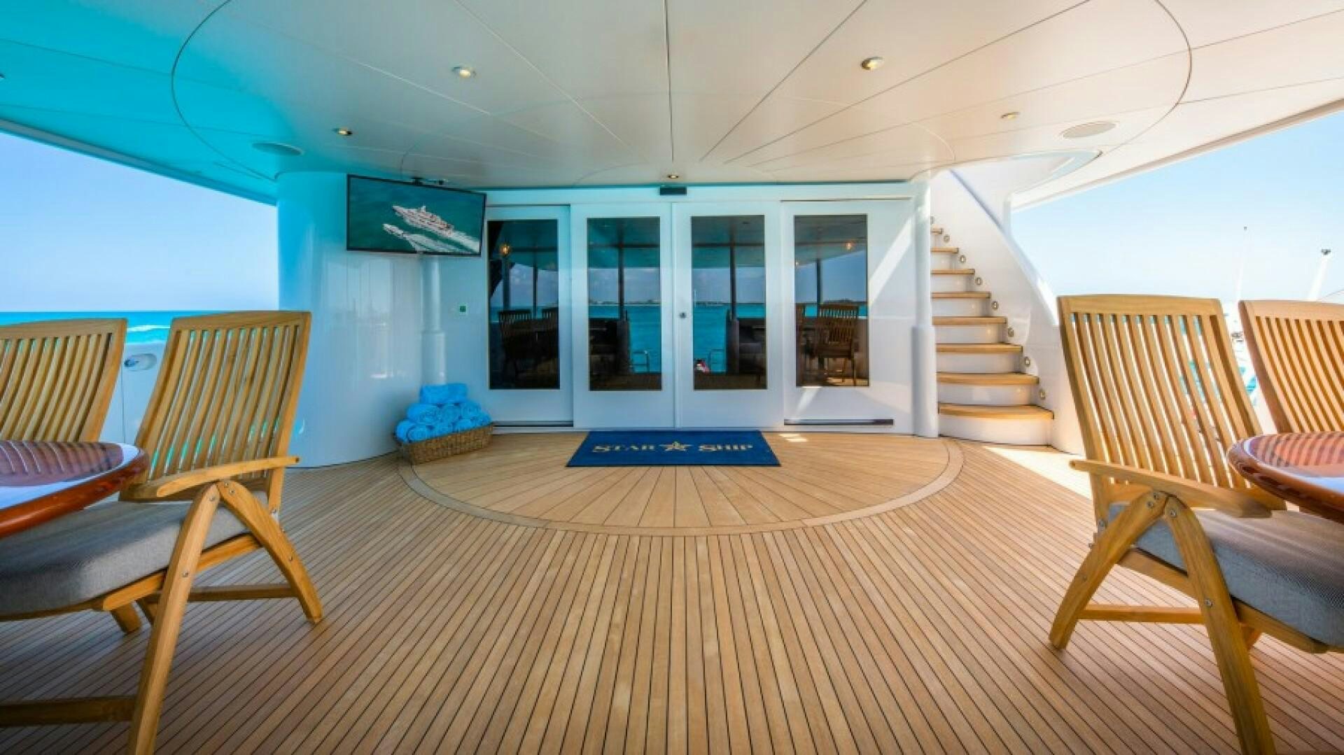 a large room with chairs and a staircase aboard STARSHIP Yacht for Sale