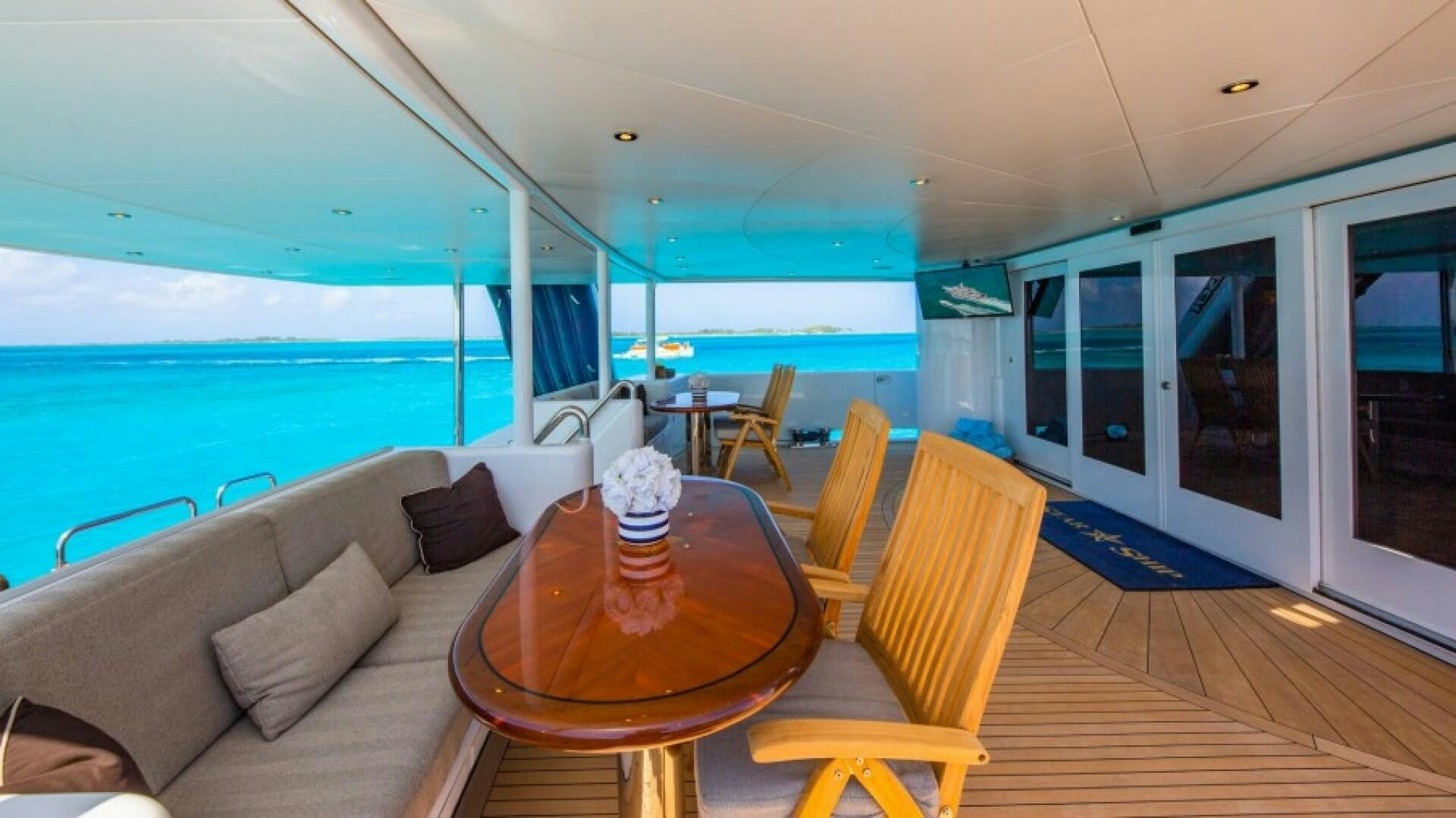 a living room with a large blue glass wall and a wood table aboard STARSHIP Yacht for Sale