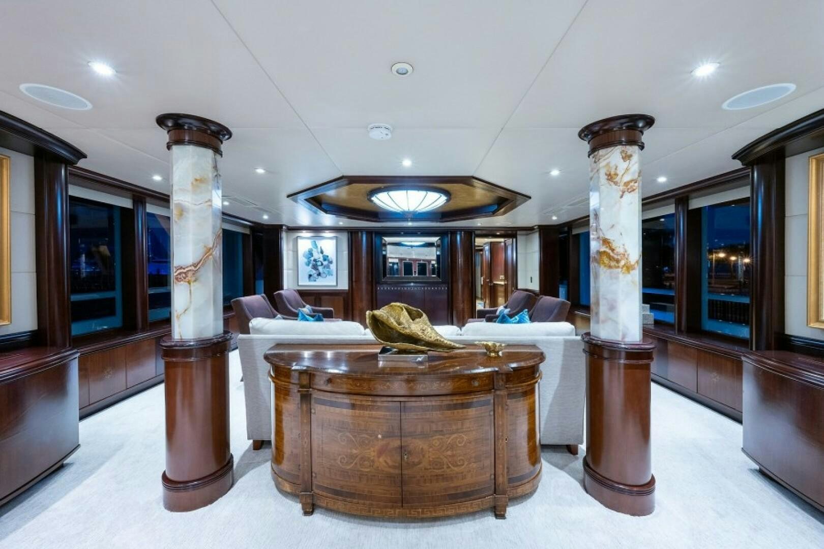 a large room with a large wood table and a large vase with a gold vase in the middle aboard STARSHIP Yacht for Sale
