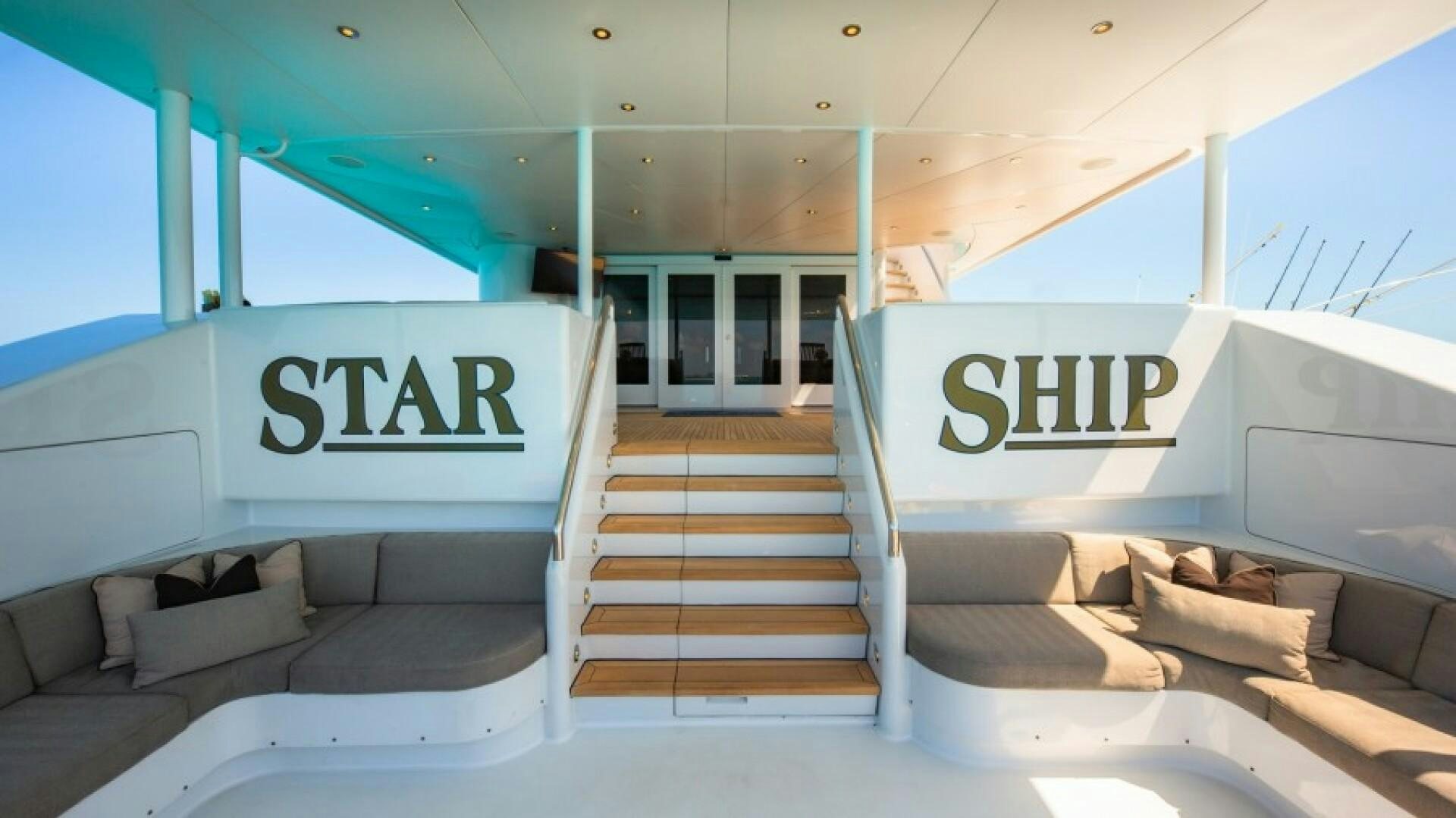 a white room with a couch and a staircase aboard STARSHIP Yacht for Sale